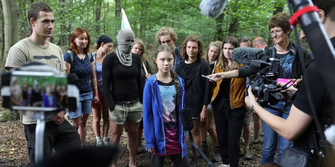 Greta Thunberg wird interviewt – im Hintergrund steht eine vermummte Aktivistin. greta Thunberg