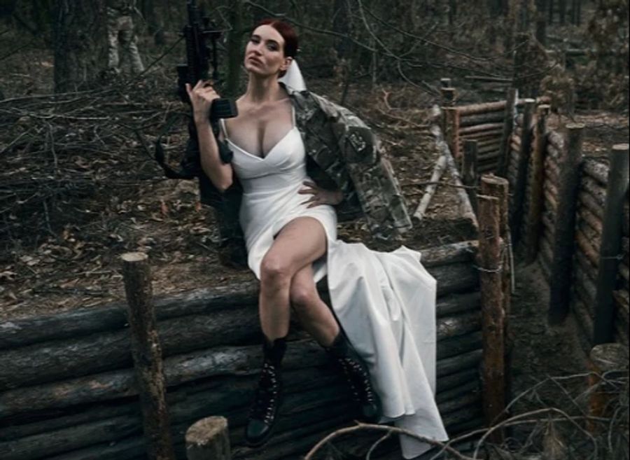 Evgeniya Emerald lässt sich im Hochzeitskleid und Waffe ablichten.