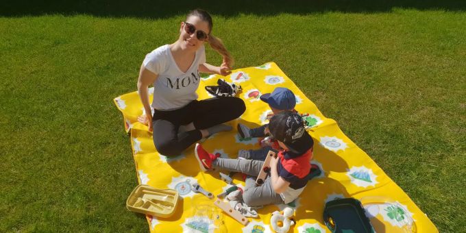 Karin liebt es mit ihren zwei Jungs im Garten zu spielen Eine Frau mit ihren zwei Jungs auf einer Picknick-Decke im Graten