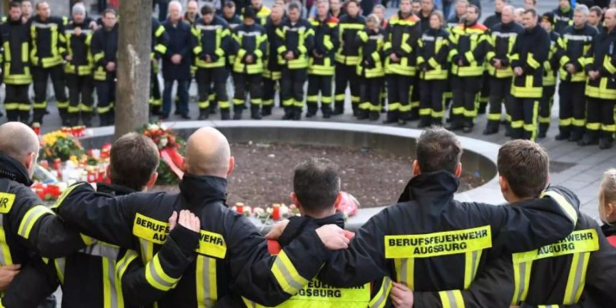 Mitglieder der Berufsfeuerwehr trauern nach der Gewalttat am Königsplatz in Augsburg. Foto: Stefan Puchner/dpa/Archiv