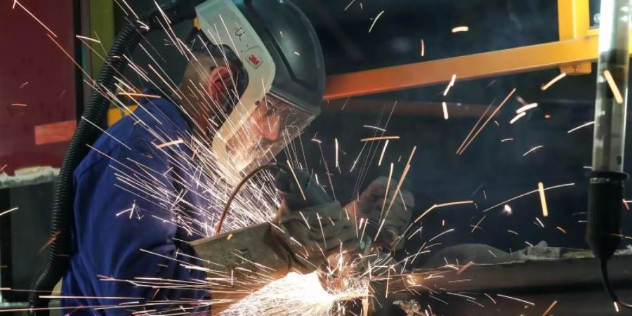 Ein Mitarbeiter eines Unternehmen im Bereich Maschinenbau schneidet mit einem Trennschleifer korrodierte Metallteile aus dem Träger eines Wagenkastens einer S-Bahn. Foto: Jan Woitas/dpa-Zentralbild/dpa