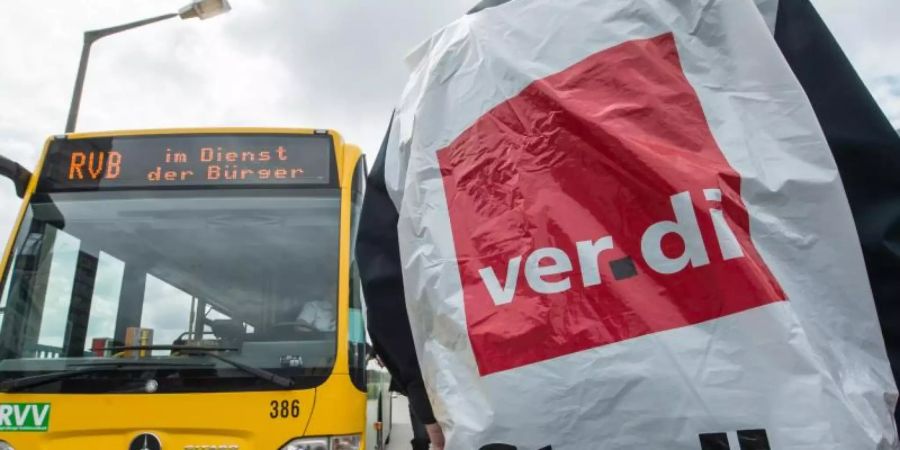 Ein streikender Busfahrer steht in Regensburg vor einem Bus. Foto: picture alliance / dpa