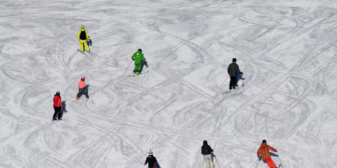 ARCHIV - 30.01.2020, Bayern, Garmisch-Partenkirchen: Skifahrer sind bei Sonnenschein auf einer Skipiste unterwegs. Wintersport-Urlauber