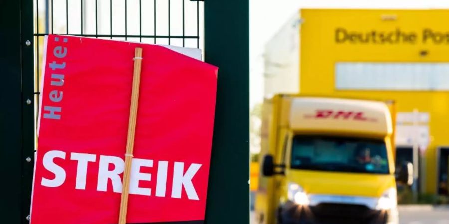 Ein Schild der Gewerkschaft Verdi mit der Aufschrift «Heute Streik» steht vor einer Deutsche-Post-DHL-Niederlassung. Foto: Moritz Frankenberg/dpa