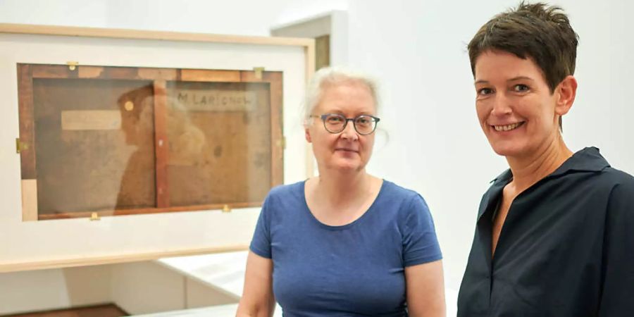 Petra Mandt (l), Restauratorin, und Rita Kersting, stellvertretende Direktorin, stehen bei einer Vorbesichtigung der Ausstellung «Russische Avantgarde im Museum Ludwig - Original und Fälschung Fragen, Untersuchungen, Erklärungen» vor der Rückseite eines Bildes des Malers M. F. Larionow. Foto: Henning Kaiser/dpa