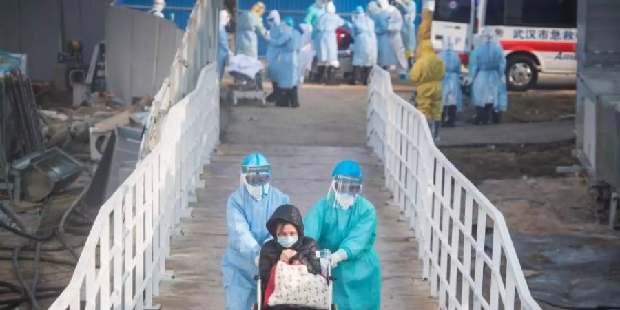 Mediziner helfen Corona-Patienten in Wuhan beim Umzug in die Isolierstationen eines neuen Behelfskrankenhauses mit rund tausend Betten. Foto: Xiao Yijiu/XinHua/dpa