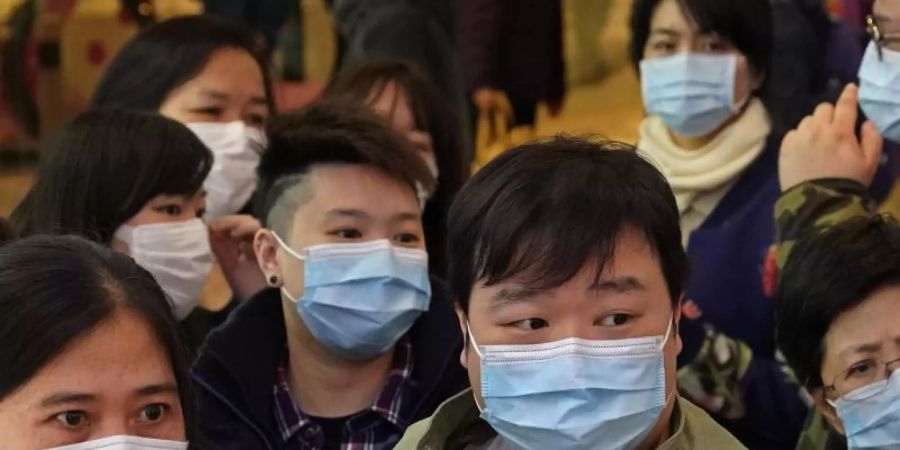 Menschen warten vor einem Geschäft in Hongkong, um Atemschutzmasken zu kaufen. Foto: Vincent Yu/AP/dpa