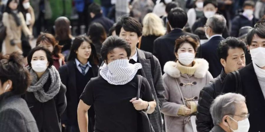 Wegen des Coronavirus tragen viele Passanten in Tokio Mundschutz. Die japanische Regierung erklärt Millionen Visa für Chinesen und Südkoreaner für ungültig. Foto: -/kyodo/dpa