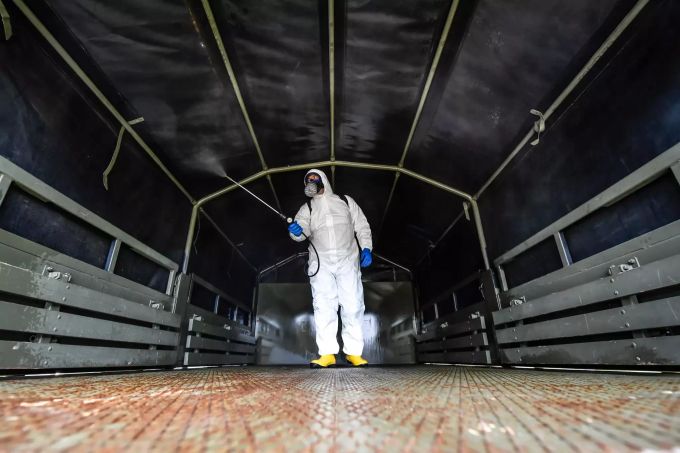 Ein Arbeiter mit Mundschutz und Schutzanzug desinfiziert einen der Militärlastwagen, der Särge mit Corona-Toten aus der Gegend von Bergamo zum Friedhof von Cinisello Balsamo transportierte. Coronavirus - Italien