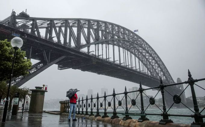 Ein Mann versucht, sich mit einem Regenschirm vor dem Regen und Sturm zu schützen. Regen in Australien