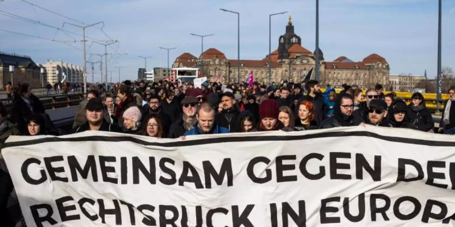 Gegendemonstranten ziehen mit einem Banner durch Dresden. Foto: Oliver Killig/dpa-Zentralbild/dpa