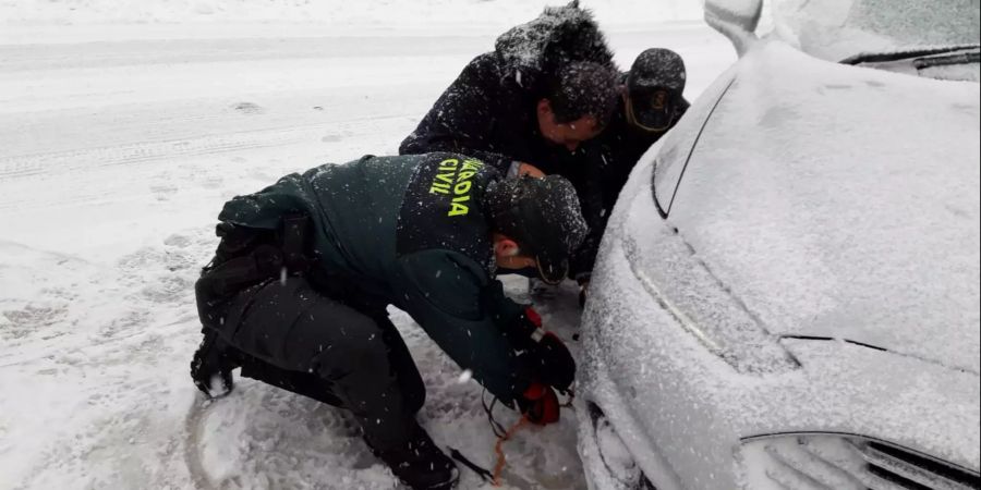 Zwei Beamte der Guardia Civil helfen einem Fahrer beim Anlegen der Schneeketten. Das Sturmtief Gloria mit starken Winden, eisigen Temperaturen und heftigen Schneefällen hat Teile Spaniens weiter fest im Griff.