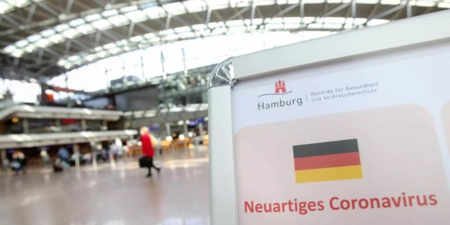 Auf einem Aufsteller der Gesundheitsbörde und des Robert Koch-Instituts wird im mässig gefüllten Hamburger Flughafen auf Verhaltensweisen in Bezug auf das Coronavirus hingewiesen. Foto: Bodo Marks/dpa