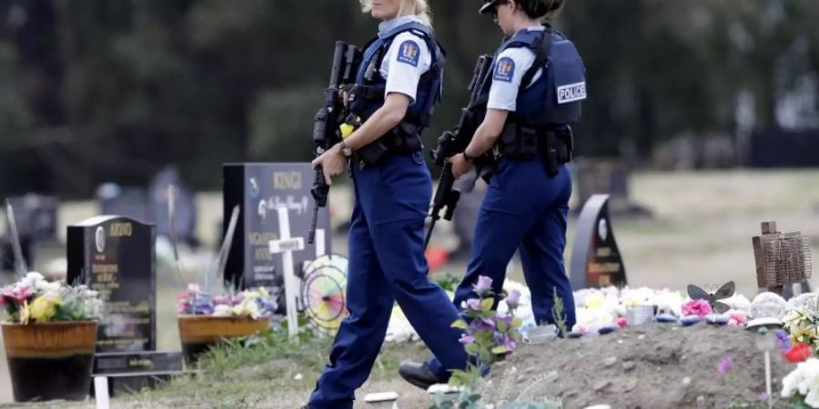 Bewaffnete Polizisten patrouillieren in der Nähe von muslimischen Gräbern auf einem Friedhof in Christchurch. Foto: Mark Baker/AP