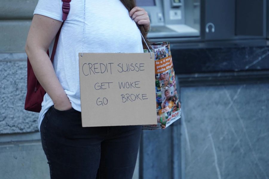 Eine Demonstrantin auf dem Paradeplatz mit einem Schild «Credit Suisse – get woke, go broke».