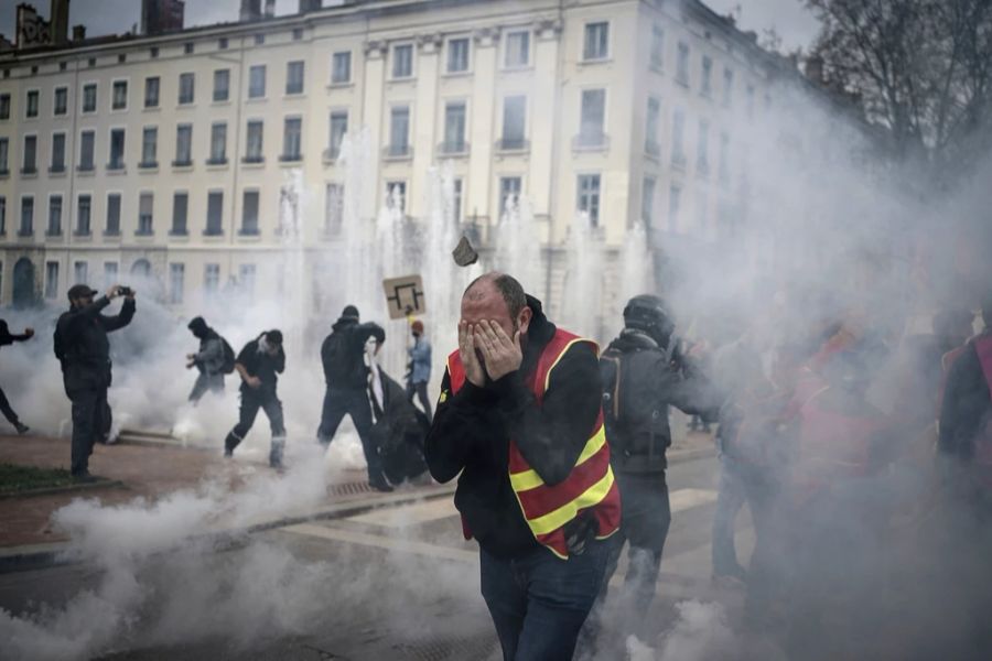 Bei der Demonstration in Lyon setzt die Polizei Tränengas ein – Demonstranten halten sich die Augen zu.