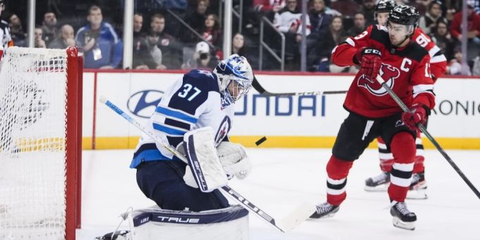 Nico Hischier (r) von den New Jersey Devils und Winnipeg Jets-Torwart Connor Hellebuyck bei einem NHL-Eishockeyspiels am Sonntag. nhl hischier