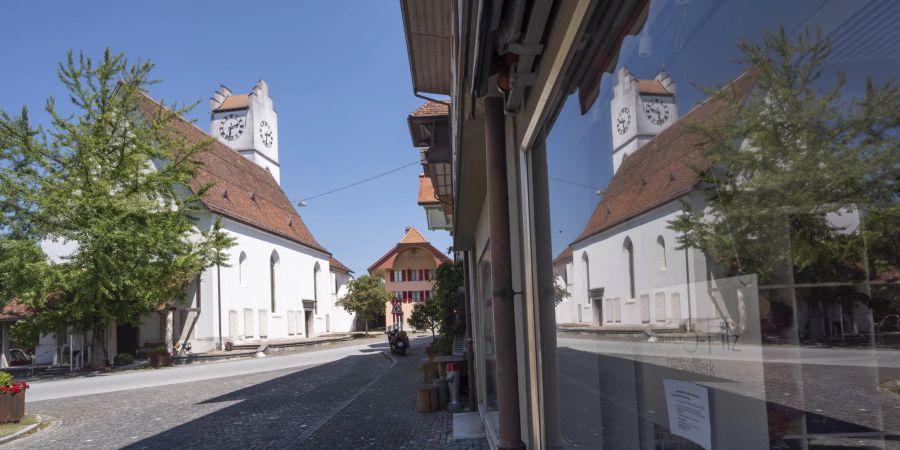 Die reformierte Kirche spiegelt sich im Schaufenster eines Geschäfts in der historischen Altstadt von Büren an der Aare.