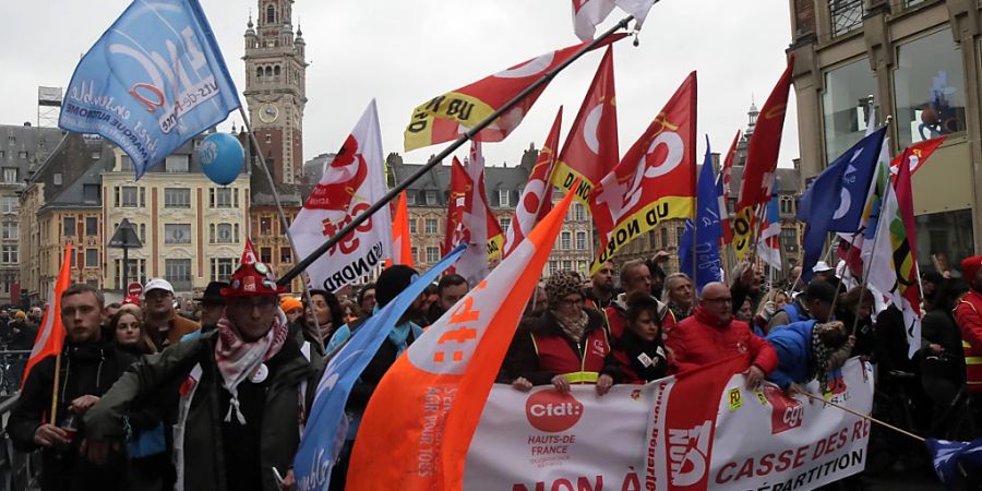 Demonstranten marschieren durch die Strassen und schwenken Fahnen während einer Demonstration gegen die geplante Rentenreform. Foto: Michel Spingler/AP/dpa