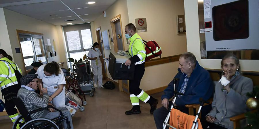 ARCHIV - Ein Mitarbeiter des Gesundheitswesens trägt eine Kiste mit dem Corona-Impfstoff von Biontech/Pfizer in das Pflegeheim Ibaneta. Foto: Alvaro Barrientos/AP/dpa