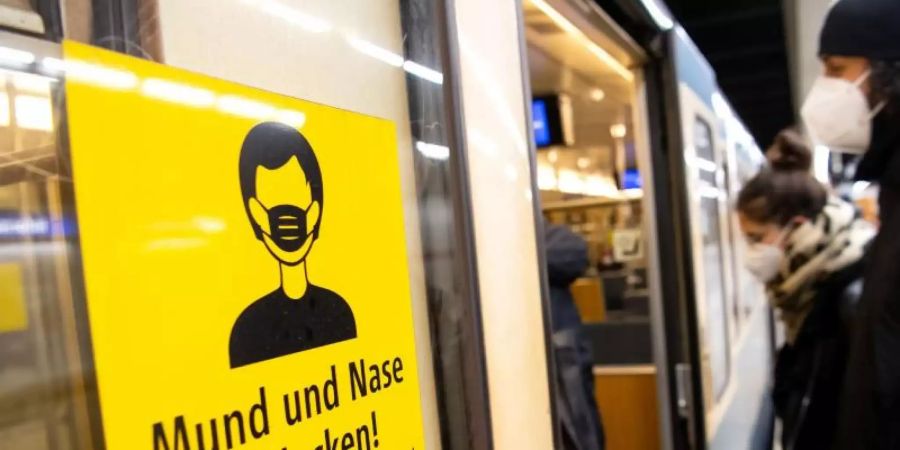 Ein Mann und eine Frau mit FFP2-Masken steigen in einer Münchner U-Bahnstation in die Bahn. Foto: Sven Hoppe/dpa