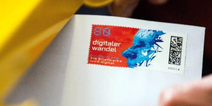 Ein Postmitarbeiter schiebt einen Brief mit einer Briefmarke mit Matrixcode in einen Briefkasten. Foto: Federico Gambarini/dpa Brief