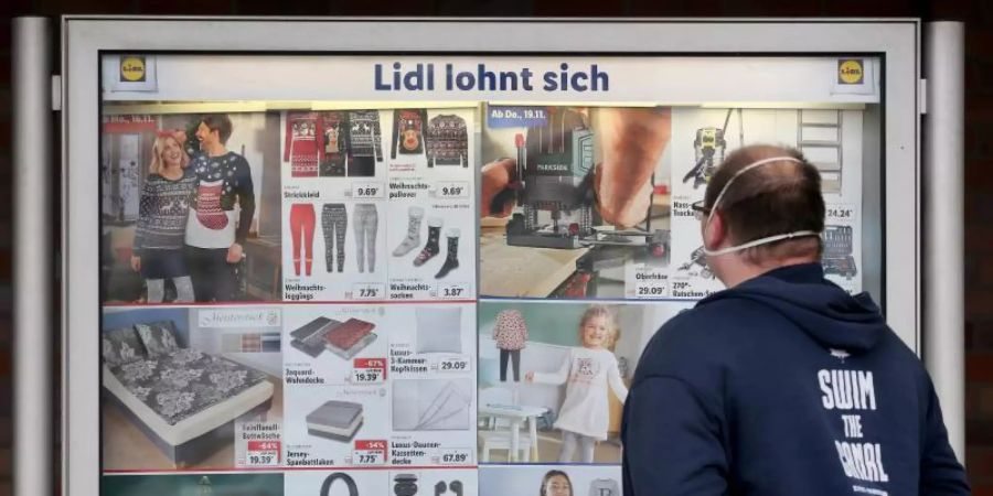 Ein Kunde einer Lidl-Filiale informiert sich an einer Werbetafel über die Sonderangebote. Foto: Roland Weihrauch/dpa