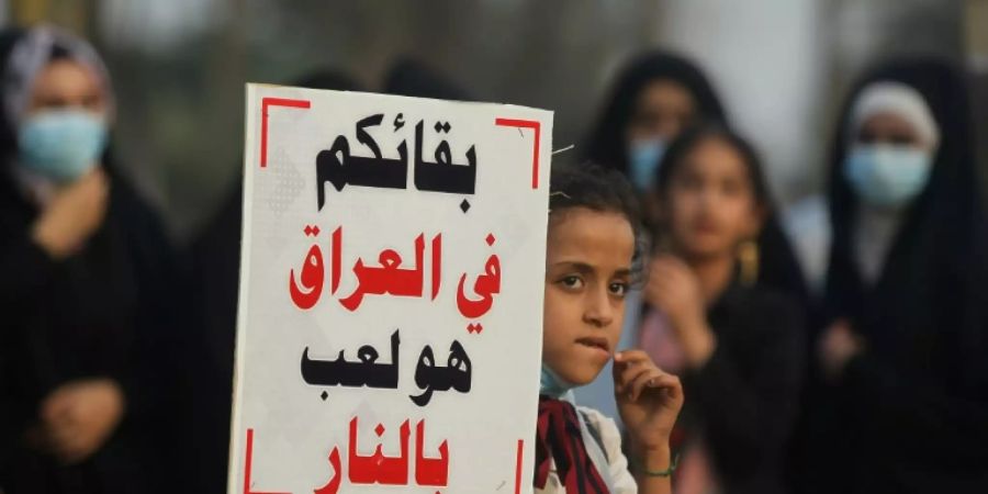 Ein Mädchen trägt ein Schild mit einer Anti-US Botschaft