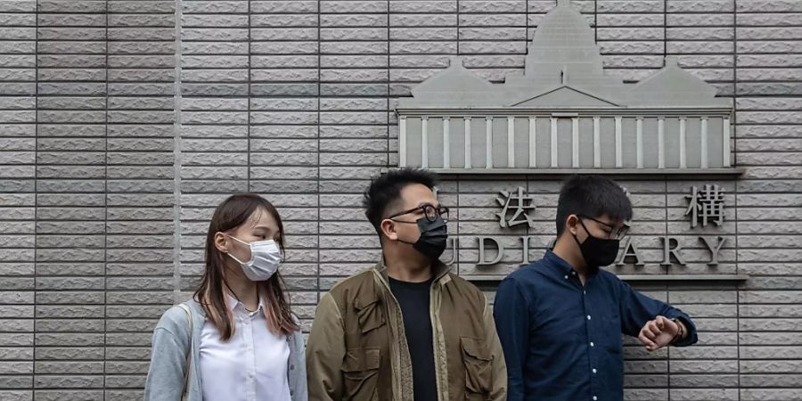 Die drei Demokratie-Aktivsten  Agnes Chow Ting (links), Ivan Lam Long Ying (Mitte) and Joshua Wong Chi-fung (rechts) vor dem West Kowloon Law Courts building in Hong Kong. Alle drei wollen sich vor dem Gericht schuldig bekennen.