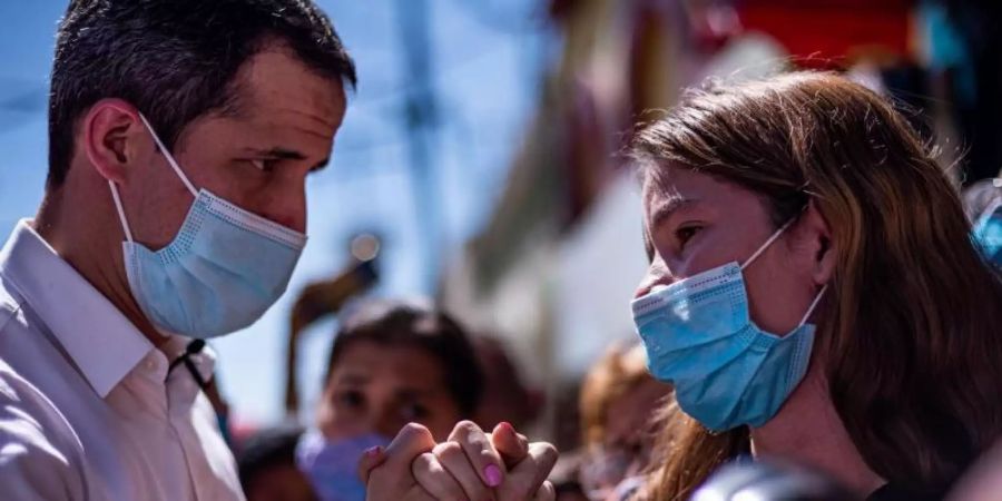 Juan Guaido (l), Oppositionsführer und selbst ernannter Interimspräsident, hält bei einem Auftritt in Valencia die Hand einer Unterstützerin. Foto: Elena Fernandez/ZUMA Wire/dpa