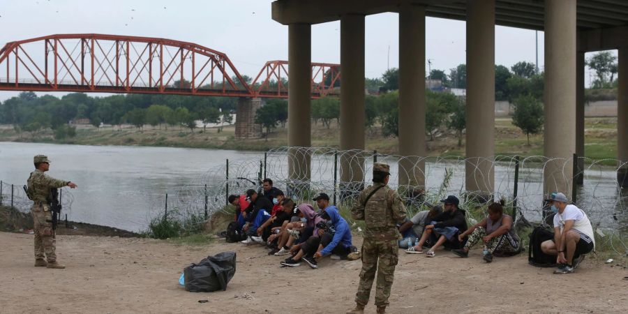 Migranten warten am Rio Grande auf die Ankunft von US-Grenzschutzbeamten. Eine Regelung der Gesundheitsbehörde CDC ermöglicht unter Verweis auf pandemiebedingte Gesundheitsrisiken, die meisten ohne gültige Papiere ins Land gelangten Menschen rasch wieder abzuschieben.