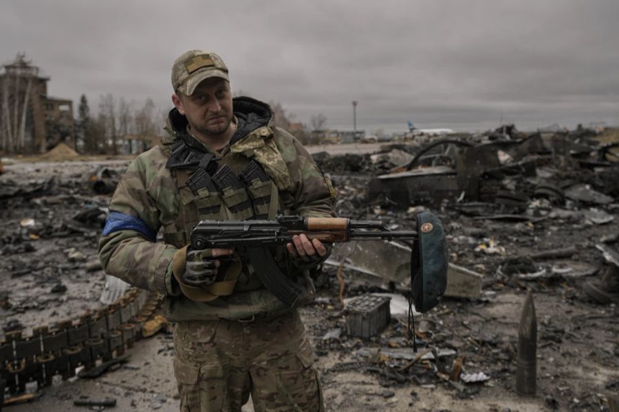 Ein ukrainischer Soldat posiert mit einem russischen Barett, das er aus zerstörten russischen Militärfahrzeugen auf seiner Waffe geborgen hat.