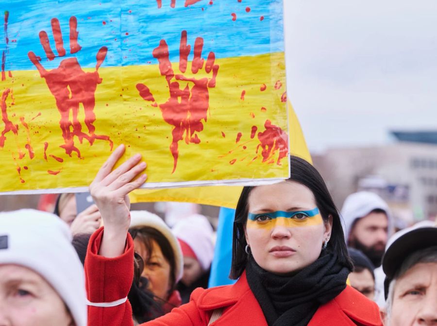 Trotz der bekannten Gräueltaten wird Russland fast nur in westlichen Demokratien negativ wahrgenommen. Abgebildet: Eine Demonstrantin in Berlin.