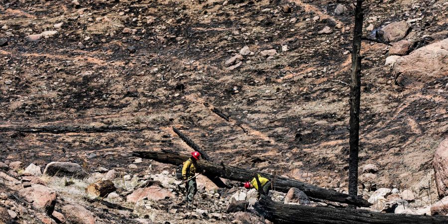 Zwei Feuerwehrleute versuchen die Glutnester eines Waldbrandes am Stadtrand von Flagstaff zu löschen.