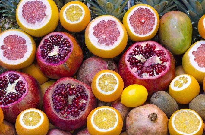 Orangen, Zitronen, Mangos, Kiwis, Ananas und Granatäpfel liegen auf einem Tisch Früchte
