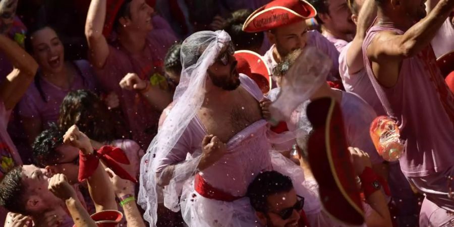 Weiss-Rot gekleidete Menschen feiern zu Beginn des «Sanfermines»-Festes, während sie auf das Abfeuern der Eröffnungsrakete «Chupinazo» warten. Foto: Alvaro Barrientos/AP