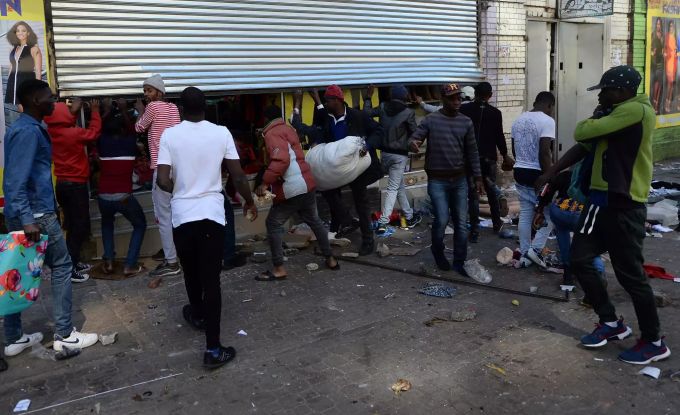 Plünderer in Südafrika machen sich mit Waren aus einem Geschäft davon. Unruhen in Südafrika