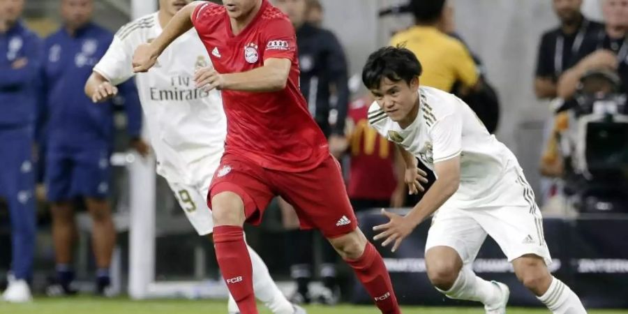 Joshua Kimmich (M) setzt sich am Bell gegen Karim Benzema (l) und Takefusa Kubo von Real Madrid durch. Foto: Michael Wyke/AP