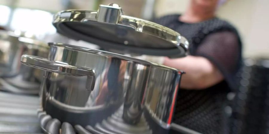 Eine Mitarbeiterin setzt im Stammwerk des Küchengeräteherstellers Württembergische Metallwarenfabrik AG (WMF) in Geislingen einen Deckel auf einen fertiggestellten Topf. Foto: Uwe Anspach