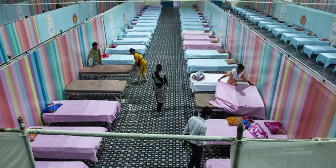 dpatopbilder - Arbeiter stellen provisorische Betten für Corona-Patienten in einer Stadionhalle auf. Foto: Anupam Nath/AP/dpa dpatopbilder - Arbeiter stellen provisorische Betten für Corona-Patienten in einer Stadionhalle auf. Foto: Anupam Nath/AP/dpa