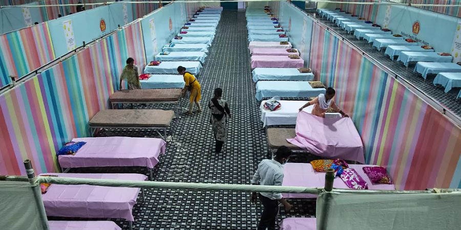dpatopbilder - Arbeiter stellen provisorische Betten für Corona-Patienten in einer Stadionhalle auf. Foto: Anupam Nath/AP/dpa
