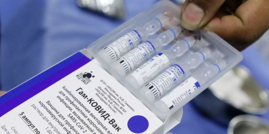 Ein Mitarbeiter des Gesundheitswesens öffnet eine Verpackung mit mehreren Dosen des Corona-Impfstoffs «Sputnik V» aus Russland. Foto: Jesus Vargas/dpa