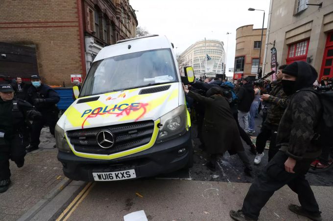 21.03.2021, Grossbritannien, Bristol: Demonstranten versuchen einen Polizeiwagen vor der Bridewell Polizeistation umzustossen während des «Kill the Bill»-Protests gegen den umstrittenen Gesetzentwurf zu Polizei und Kriminalität. "Kill the Bill"-Protest in Bristol