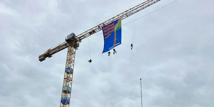 Aktivisten enthüllten auf einem Baukran beim Bundesplatz in Bern ein Greenpeace-Transparenz.