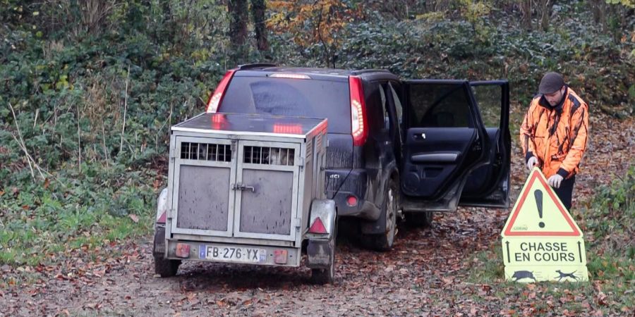 Ein französischer Jäger stellt ein Schild auf, das Spaziergänger vor einer Drückjagd warnt.