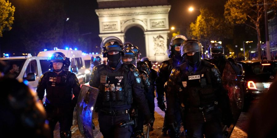 Polizisten patrouillieren vor dem Arc de Triomphe auf der Champs Élysées.