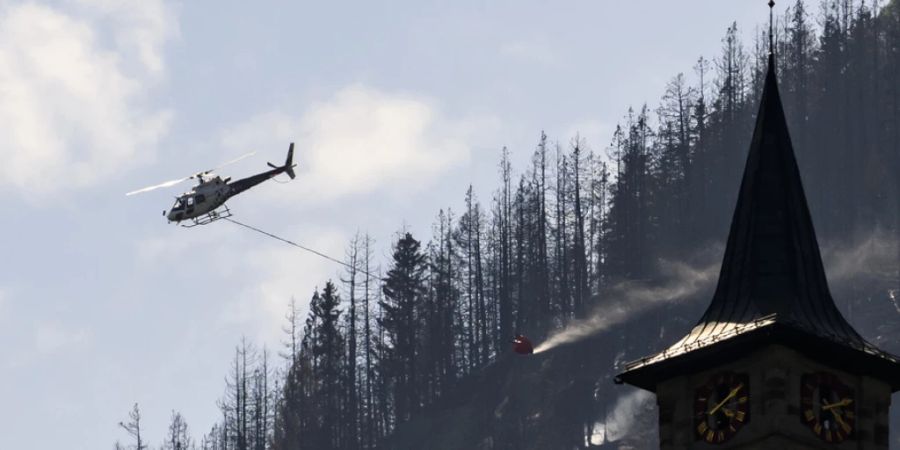 Ein Helikopter der Air Zermatt lässt Wasser über dem Brandgebiet ab.