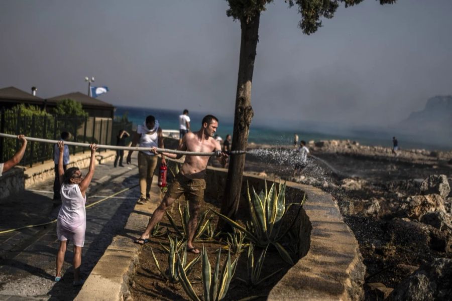 Nebst Rettungskräften versuchen auch die Bewohnerinnen und Bewohner der Ferieninsel gegen die Flammen vorzugehen.