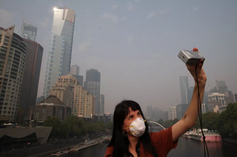 Eine Touristin schiesst ein Selfie im versmogten Melbourne.