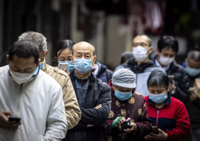 Menschen mit Schutzmasken warten vor einem Lebensmittelladen in Guangzhou, China coronavirus china